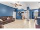 Bright open concept living space with blue walls, tile flooring, a brown leather sofa and comfortable furniture at 12040 Penzance Ln, New Port Richey, FL 34654
