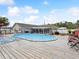 Large above-ground pool surrounded by a wooden deck, lounge chairs, and well-maintained landscaping on a sunny day at 13052 Drysdale St, Spring Hill, FL 34609