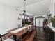 Bright dining room featuring dark wood floors, a long wood table with benches, and modern light fixture at 13052 Drysdale St, Spring Hill, FL 34609