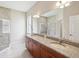 A spacious bathroom featuring double sinks, granite counters, large mirror and glass enclosed shower at 13618 Niti Dr, Hudson, FL 34669