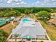 Aerial view of the community clubhouse, swimming pool, and tennis courts amid lush green landscaping at 13618 Niti Dr, Hudson, FL 34669