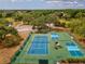 Aerial image showcasing multiple community tennis and pickleball courts nestled within a lush, green landscape at 13618 Niti Dr, Hudson, FL 34669