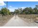 Long gravel driveway leading to a home with mature trees and a secure gated entrance for added privacy at 14545 Battenwood Dr, Spring Hill, FL 34610