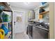 Well-equipped laundry room with washer, dryer, storage shelves, and access to the outdoors at 14545 Battenwood Dr, Spring Hill, FL 34610