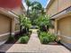 Inviting brick-paved walkway between buildings, adorned with lush landscaping and palm trees, enhancing the community's appeal at 21008 Sunpoint Way # 204, Lutz, FL 33558