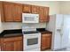 Bright kitchen features wood cabinets, black countertops, and white appliances at 21041 Sunpoint Way # 202, Lutz, FL 33558