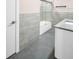 Stylish bathroom features a contemporary vanity, marbled tile, and a glass-enclosed tub, creating a relaxing and modern space at 2660 Orangewood Ct, Palm Harbor, FL 34684