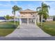 Two-story coastal home with a covered parking area, balcony, and lush tropical landscaping at 3340 Oleander Dr, Hernando Beach, FL 34607