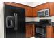 Close up of black appliances, wood cabinets, and granite countertops of updated kitchen at 3410 Thistledown Ln, Land O Lakes, FL 34638
