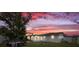Exterior view of backyard with a sunroom addition and a vivid sunset backdrop at 3638 Bigelow Dr, Holiday, FL 34691