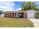 View of the home's brick facade, covered porch, and well-maintained lawn with a clear blue sky at 3638 Bigelow Dr, Holiday, FL 34691