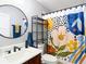 Bright bathroom with a round mirror, decorative shower curtain, and dark wood vanity at 4207 Fishermans Lake Dr, Lutz, FL 33558