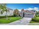 Inviting gray home boasts mature palm trees, lush landscaping, and a wide driveway leading to a two-car garage at 4207 Fishermans Lake Dr, Lutz, FL 33558