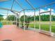 Bright screened-in patio offering a view of the yard with a golf cart in the distance at 4207 Fishermans Lake Dr, Lutz, FL 33558
