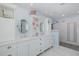 Bright bathroom featuring double vanity, decorative mirrors, and tiled walk-in shower at 5040 Waterside Dr, Port Richey, FL 34668