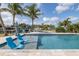 Relaxing poolside view with blue sunbeds and table under the palm trees on a sunny day at 5040 Waterside Dr, Port Richey, FL 34668