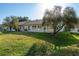 A spacious backyard with a lush lawn, trees and the back of the house with several windows to let natural light in at 5931 Precious View Ct, New Port Richey, FL 34655