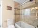 Bright bathroom featuring a tub with shower, tile surround, glass door and neutral-toned walls at 606 Howell Ave, Brooksville, FL 34601