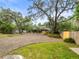 View of home and front yard featuring a gravel driveway and mature shade trees enhancing the property's curb appeal at 606 Howell Ave, Brooksville, FL 34601