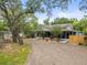 Charming home with a screened-in porch and a gravel driveway surrounded by lush trees and landscaping at 606 Howell Ave, Brooksville, FL 34601