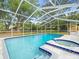 Screened-in pool with an attached hot tub and stone pool deck at 606 Howell Ave, Brooksville, FL 34601
