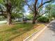 Charming home enveloped by mature trees, complemented by a water well feature, lush lawn, and street view at 606 Howell Ave, Brooksville, FL 34601