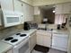 Well-lit kitchen featuring white cabinets and view of the dining and living room at 6338 Spring Flower Dr # 15, New Port Richey, FL 34653