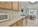 Galley kitchen includes light wood cabinets, white countertops, stainless steel sink, dishwasher and white microwave at 7644 St Andrews Blvd # 0, Weeki Wachee, FL 34613