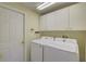 This laundry room features a washer, dryer, cabinets and a door at 7827 Starfire Way, New Port Richey, FL 34654