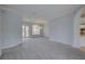Light-filled living room featuring neutral walls, gray carpet, and a view to the kitchen at 7827 Starfire Way, New Port Richey, FL 34654