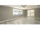 Bedroom with wood-look tile flooring, ceiling fan, windows, and a sliding glass door at 8522 Inwood Dr, Hudson, FL 34667
