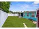 Expansive backyard featuring a well-maintained lawn, white fencing, and a cozy screened-in porch at 9015 Mark Twain Ln, Port Richey, FL 34668
