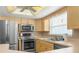The kitchen has stainless steel appliances, wooden cabinets and tiled backsplash at 9015 Mark Twain Ln, Port Richey, FL 34668