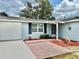 Charming single-story home showcasing blue siding, brick walkway and well-maintained landscaping at 9034 Cochise Ln, Port Richey, FL 34668