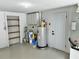 Brightly lit garage area with shelves, cabinets, and a water heater at 9034 Cochise Ln, Port Richey, FL 34668