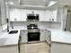 Bright kitchen featuring white cabinets, marble countertops, and stainless steel appliances at 9034 Cochise Ln, Port Richey, FL 34668