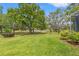 The grassy backyard has mature trees and landscaping at 9245 Grand Cypress Dr, Spring Hill, FL 34613
