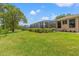 View of the spacious, lush backyard from beside the home and lanai at 9245 Grand Cypress Dr, Spring Hill, FL 34613
