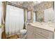 Well-lit bathroom features decorative wallpaper, white cabinets and hardware at 9245 Grand Cypress Dr, Spring Hill, FL 34613