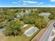 Aerial view of community bocce ball courts next to lake and tennis courts amidst mature landscaping and neighborhood streets at 9245 Grand Cypress Dr, Spring Hill, FL 34613