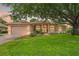 Charming single-story home with a lush green lawn and mature trees providing shade at 9245 Grand Cypress Dr, Spring Hill, FL 34613