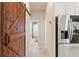Hallway view of the stainless steel refrigerator and sliding barn door leading to a pantry and an adjacent bathroom at 9245 Grand Cypress Dr, Spring Hill, FL 34613