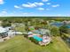 Beautiful aerial view of the community pool, tennis court, and surrounding landscape with mature trees and clubhouse at 9245 Grand Cypress Dr, Spring Hill, FL 34613