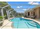 A screened-in pool with blue water is steps from the lanai on a sunny day at 9245 Grand Cypress Dr, Spring Hill, FL 34613