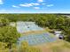 Aerial view of multiple well-maintained tennis and pickleball courts surrounded by mature trees in a vibrant community at 9245 Grand Cypress Dr, Spring Hill, FL 34613