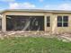 Back exterior view of the house featuring a large, screened-in patio and a grass backyard at 10187 Holly Berry Dr, Weeki Wachee, FL 34613