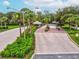 Scenic entrance to a gated community, featuring lush landscaping, mature trees, and a welcoming guardhouse at 10187 Holly Berry Dr, Weeki Wachee, FL 34613