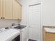 Functional laundry room with upper cabinets, granite countertop sink, and modern appliances at 10187 Holly Berry Dr, Weeki Wachee, FL 34613