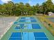 A bird's-eye view of a modern pickleball complex features multiple blue and green courts for community members at 10187 Holly Berry Dr, Weeki Wachee, FL 34613