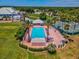 Aerial view of a community pool with palm trees, lounge chairs, spa, and tennis courts surrounded by lush landscaping at 10187 Holly Berry Dr, Weeki Wachee, FL 34613